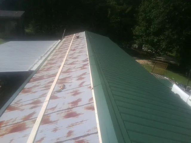 Old rusted panels beside newly installed green metal roofing — Wind Damage Roof Repair by Roofing Brothers in Windermere