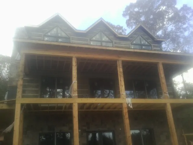 Dormers and porch framing on a large log home under construction — Roof Coating work by our crew in Windermere